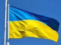 Vlající vlajka Ukrajiny a na pozadí je modrá obloha.